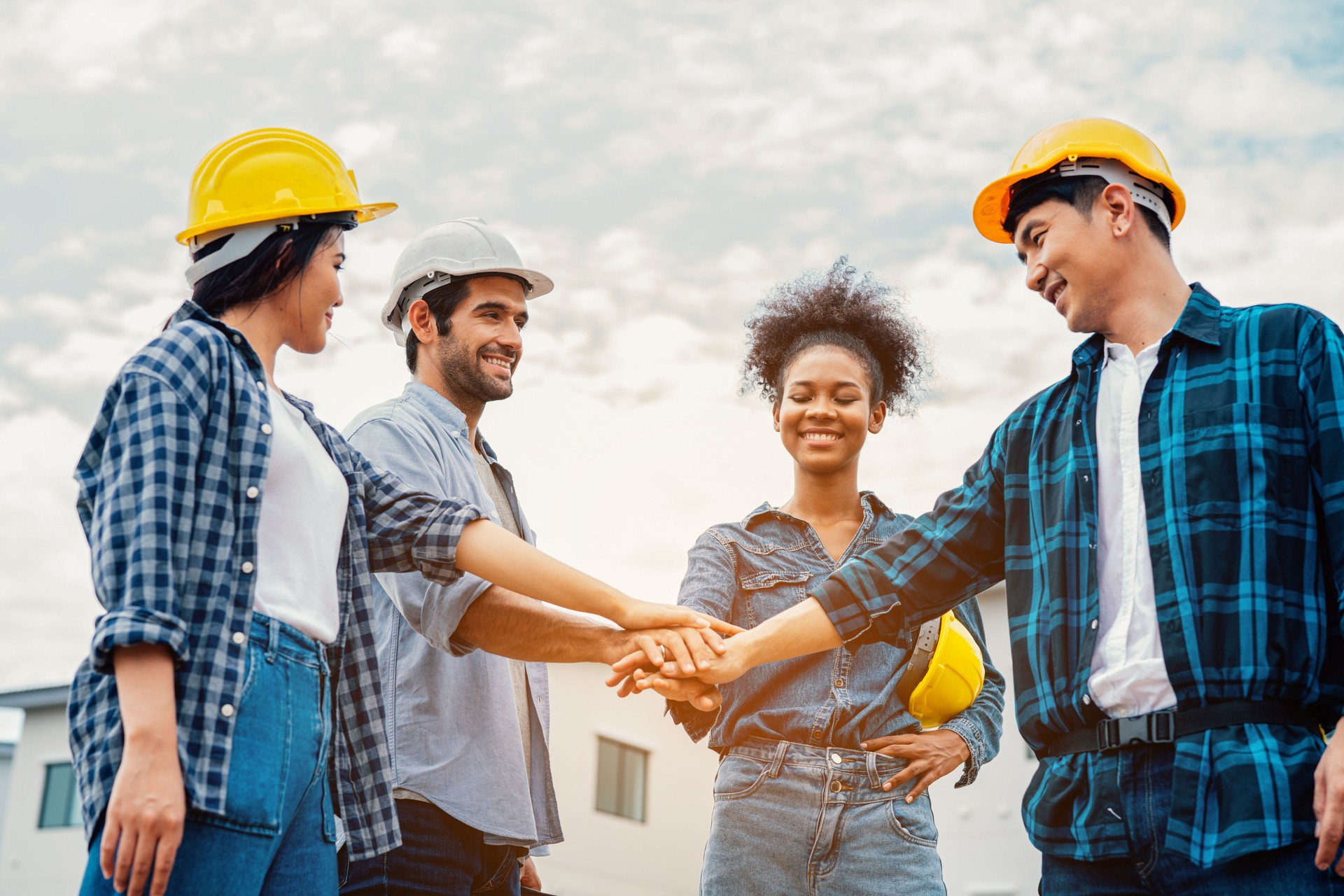 Team of engineer construction workers join hands together on construction site.